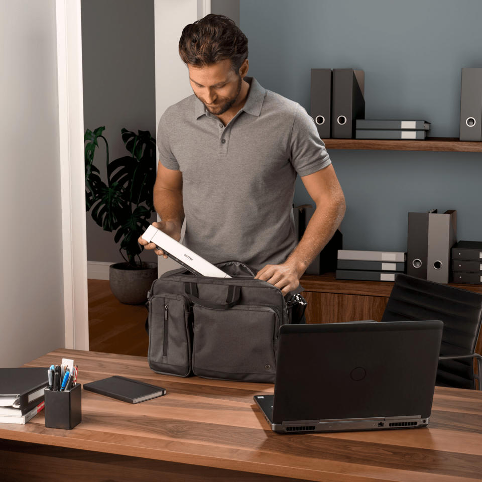 a man putting the brother portable scanner into a briefcase