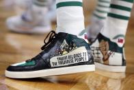 Boston Celtics' Enes Kanter wears a political message on his shoes during the first half of the team's NBA basketball game against the Milwaukee Bucks, Friday, Nov. 12, 2021, in Boston. (AP Photo/Michael Dwyer)