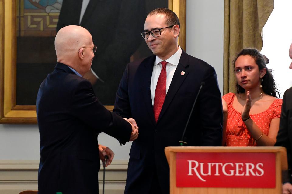 (from left) Mark Angelson, chair of the Rutgers Board of Governors, shakes hands with Jonathan Holloway, the new president of Rutgers University, as his daughter and family members look on. Holloway, the universityÕs first non-white president, was announced in New Brunswick on Tuesday, Jan. 21, 2020.