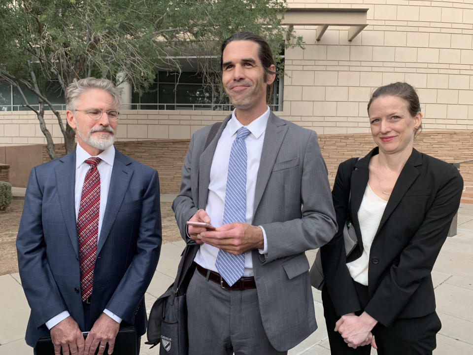 Scott Warren, center, of Ajo, Ariz. celebrates with his attorneys Amy Knight, right, and Greg Kuykendall outside court in Tucson, Ariz. on Wednesday, Nov. 20, 2019, after being acquitted of two counts of harboring in a case that garnered international attention. Prosecutors said Warren illegally helped two migrants avoid authorities. He said he was fulfilling his humanitarian duties by helping two injured men. (AP Photo/Astrid Galvan)