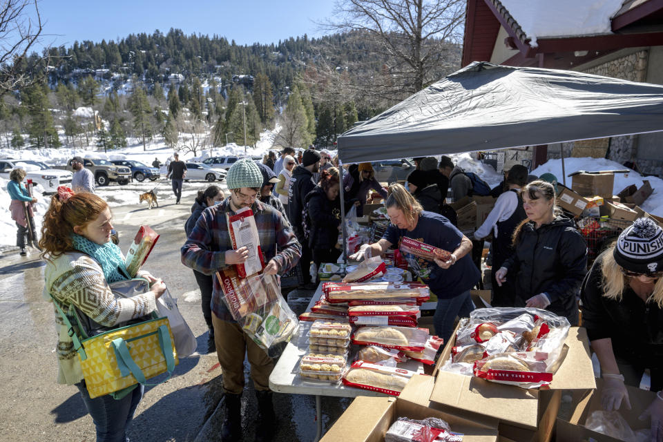 Crestline residents receive free food at a tent set up in front of the Goodwin & Son's Market in Crestline, Calif., Friday, March 3, 2023. Heavy snowfall has caused delivery truck access issues, leading to a food shortage in the area. (Watchara Phomicinda/The Orange County Register via AP)