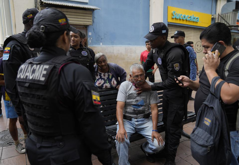 Municipal police attend to injured lottery vendor Lizardo Heredia in downtown Guayaquil, Ecuador, Friday, Aug. 18, 2023. According to police, an attacker used a piece of broken bottle to try to rob him, and the attacker was detained. (AP Photo/Martin Mejia)