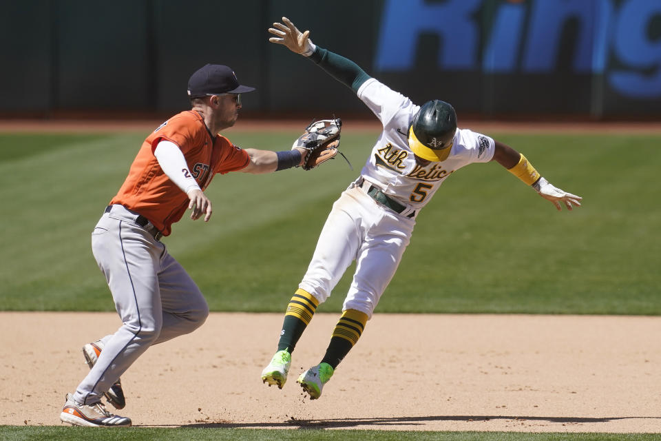 Houston Astros third baseman Alex Bregman, left, reaches to tag out Oakland Athletics' Tony Kemp during the seventh inning of a baseball game in Oakland, Calif., Thursday, May 20, 2021. (AP Photo/Jeff Chiu)