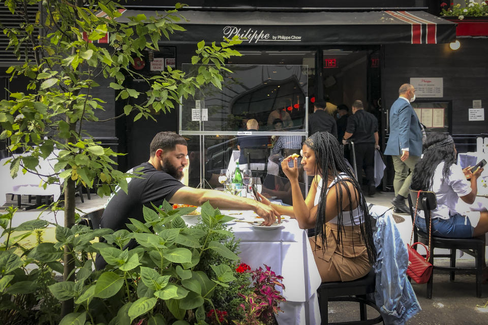 Diners eat al fresco due to COVID-19 concerns in midtown Manhattan, Friday, June 26, 2020, in New York. New York City Mayor Bill de Blasio says he's delaying the planned resumption of indoor dining at restaurants in the city out of fear it would ignite a spike in coronavirus infections. (AP Photo/John Minchillo)