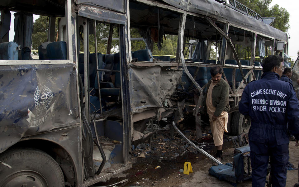 Pakistani investigators survey a damaged police bus at the site of bombing in Karachi, Pakistan, Thursday, Feb. 13, 2014. A bomb attack killed at least several police officers and wounded dozens others in Pakistan's southern city of Karachi on Thursday. (AP Photo/Shakil Adil)