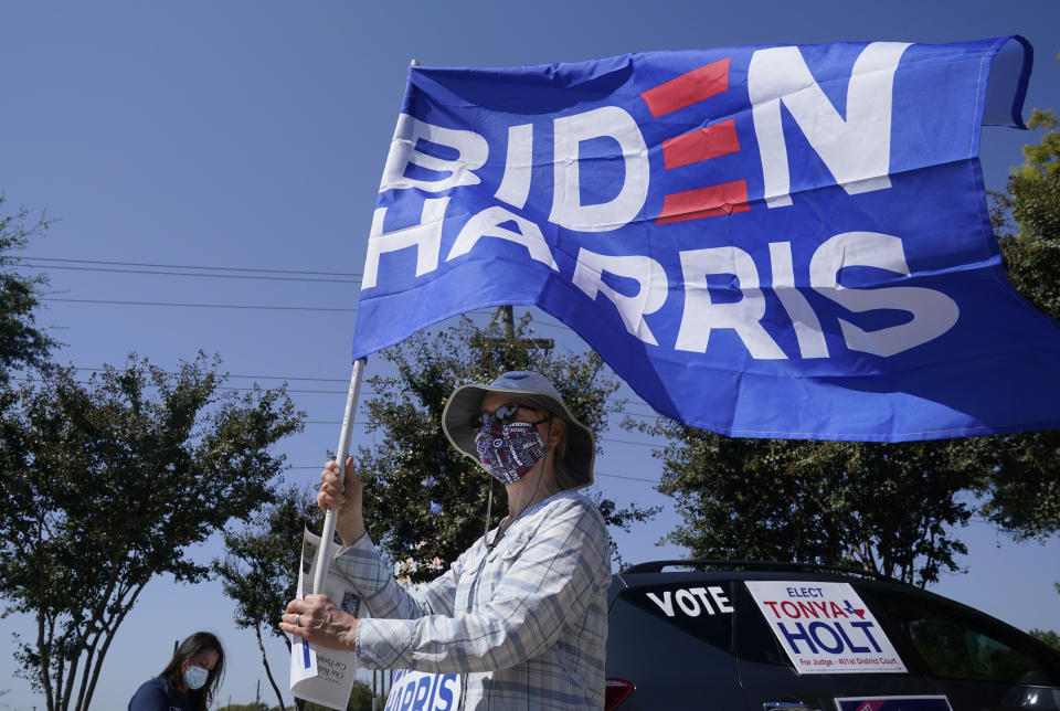 A Michell Rawlins shows her support of Democratic presidential candidate former Vice President Joe Biden by holding a flag in the wind Sunday, Oct. 11, 2020, in Plano, Texas. Democrats in Texas are pressing Joe Biden to make a harder run at Texas with less than three weeks until Election Day. (AP Photo/LM Otero)