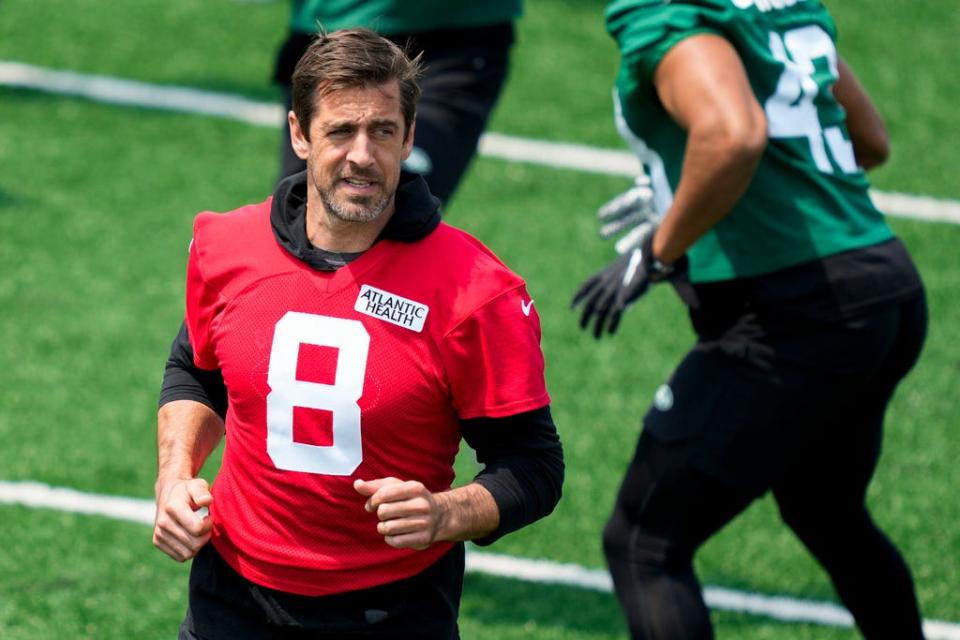 New York Jets quarterback Aaron Rodgers performs stretching drills with his teammates.