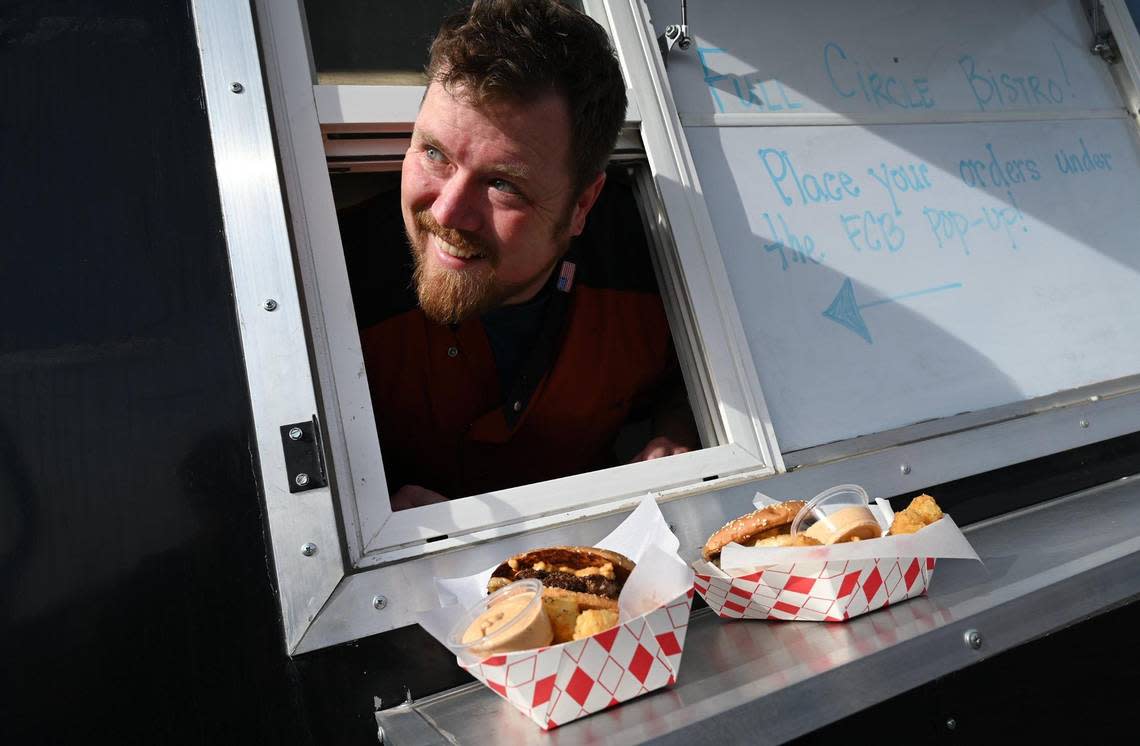 Full Circle Brewing Food Service Manager Jacob Holder pops his head out of the new Full Circle Bistro food truck window with smashburger and chicken sandwich orders to go Saturday, Feb. 4, 2023 in Fresno.