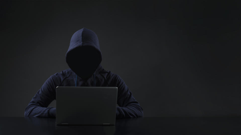 Hooded man in front of computer.