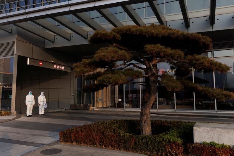 Epidemic prevention workers in protective suits guard the entrance to an office building in the Central Business District (CBD) as outbreaks of the coronavirus disease (COVID-19) continue in Beijing