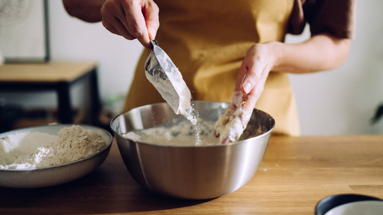 adding flour to wet dough in a bowl