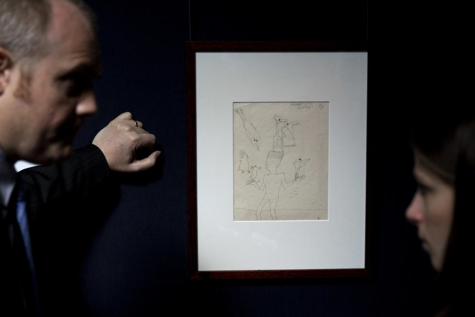 A Sotheby's employee, left, speaks to a journalist beside an untitled illustration of a boy with six birds by the late Beatles members John Lennon at the auction house's premises in central London, Friday, March 21, 2014. The ink drawing in black with editorial notes is estimated to fetch between 12,000 to 15,000 pounds ($19,795 to $24,744 or 14,360 to 24,744 euro) in a June 4 New York sale of Lennon autograph drawings and manuscripts produced for his books "In His Own Write" and "A Spaniard in the Works". (AP Photo/Matt Dunham)