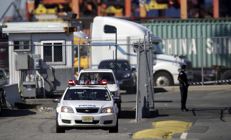 A police official stands near the entrance to a terminal at Port Newark, Wednesday, June 27, 2012, in Newark, N.J. The Coast Guard suspects there are stowaways in a container that was loaded on a ship. Coast Guard spokesman Charles Rowe says a boarding party heard sounds consistent with people coming from the container. The container was loaded aboard The Villa D'Aquarius in India. The manifest says the container was carrying machine parts to be unloaded in Norfolk, Va. (AP Photo/Julio Cortez)