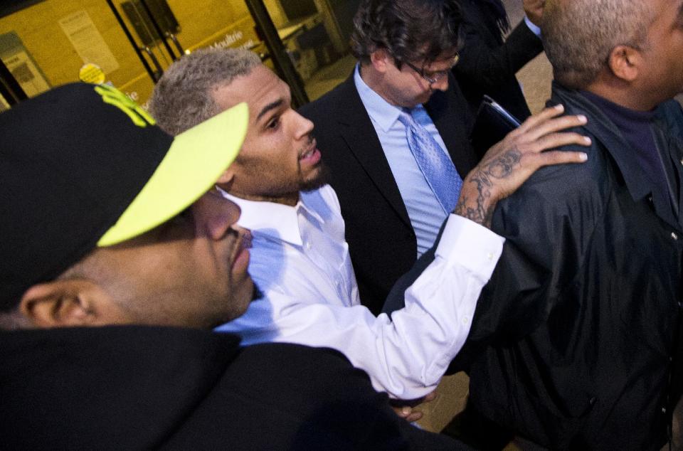 Singer Chris Brown is surrounded by bodyguards as he departs the H. Carl Moultriel courthouse Monday, Oct. 28, 2013, with one of his attorney's, Danny Onorato, second from right, in Washington. A charge against the Grammy Award-winning R&B singer has been reduced to a misdemeanor and he was ordered released after his arrest Sunday following an altercation outside a Washington hotel. (AP Photo/ Evan Vucci)