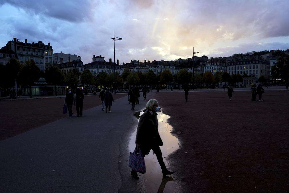 A woman wearing a mask walks in the street in the center of Lyon, central France, Wednesday, Oct. 28, 2020. France is bracing for a potential new lockdown as the president prepares a televised address Wednesday aimed at stopping a fast-rising tide of virus patients filling French hospitals and a growing daily death toll. French markets opened lower on expectations that President Emmanuel Macron will announce some kind of lockdown Wednesday. (AP Photo/Laurent Cipriani)