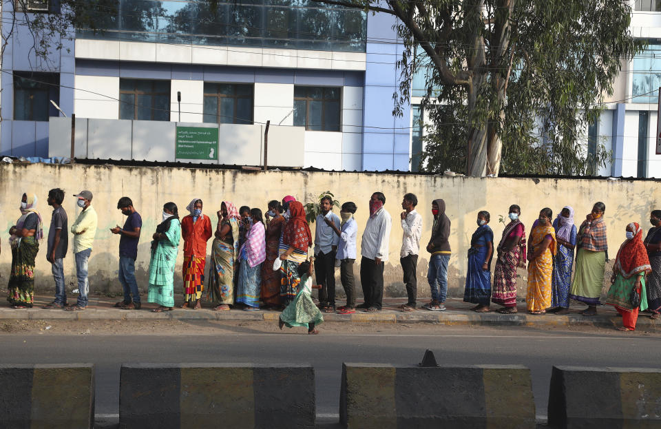 Indians wearing face masks as a precaution against coronavirus stand in a queue to receive free food outside a maternity hospital in Hyderabad, India, Monday, Jan. 18, 2021. India started inoculating health workers Saturday in what is likely the world's largest COVID-19 vaccination campaign, joining the ranks of wealthier nations where the effort is already well underway. (AP Photo/Mahesh Kumar A.)