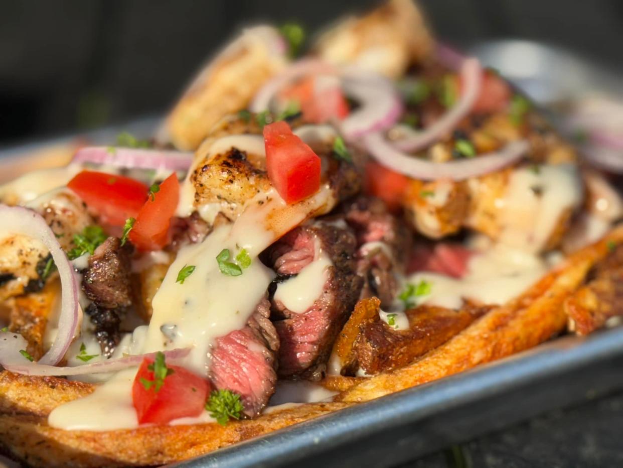 A Saturday night Surf and Turf Loaded Pots special with hand cut fries topped by ribeye steak, shrimp, queso, bacon and veggie garnishes at Chef Lo on the Go inside the Main Street Food & Beverage Food Hall.