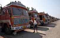 A man walks past parked supply trucks at a yard during a 21-day nationwide lockdown to limit the spreading of coronavirus disease (COVID-19), on the outskirts of Kolkata