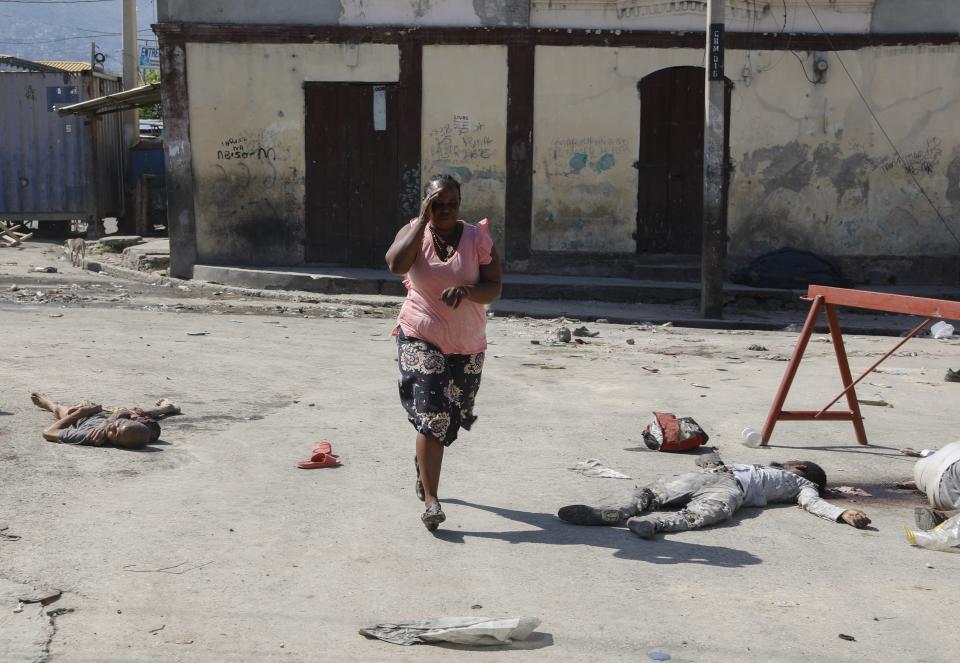 A woman walks past bodies of inmates outside the National Penitentiary in Port-au-Prince, Haiti, Sunday, March 3, 2024. Hundreds of inmates fled Haiti's main prison after armed gangs stormed the facility overnight. (AP Photo/Odelyn Joseph)