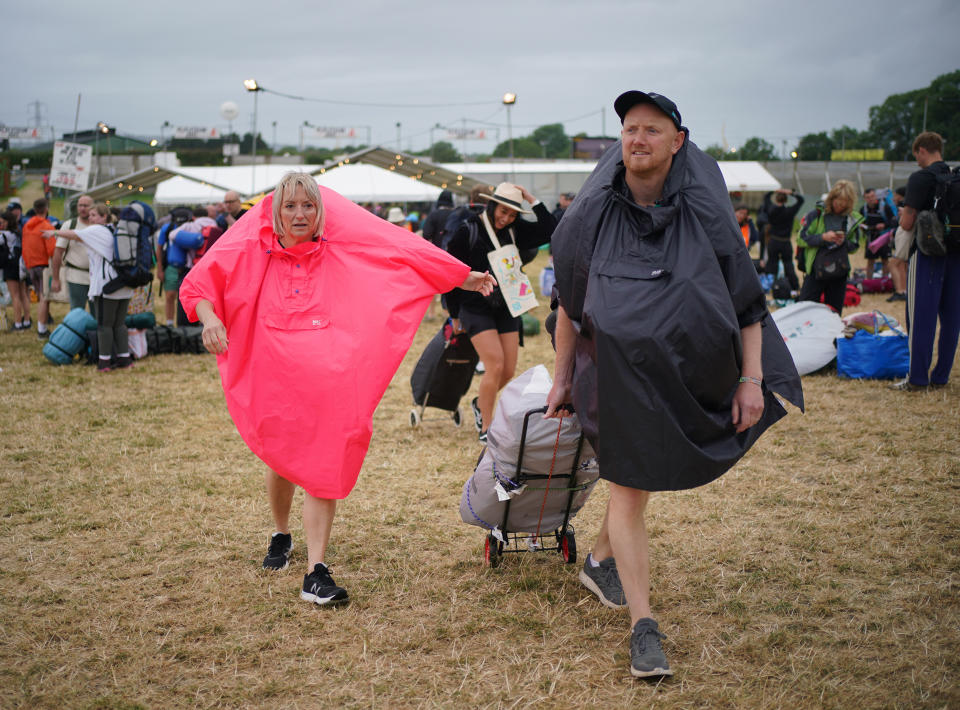 Festivalgoers arrive during a rain shower at the Glastonbury Festival on Thursday. (PA)