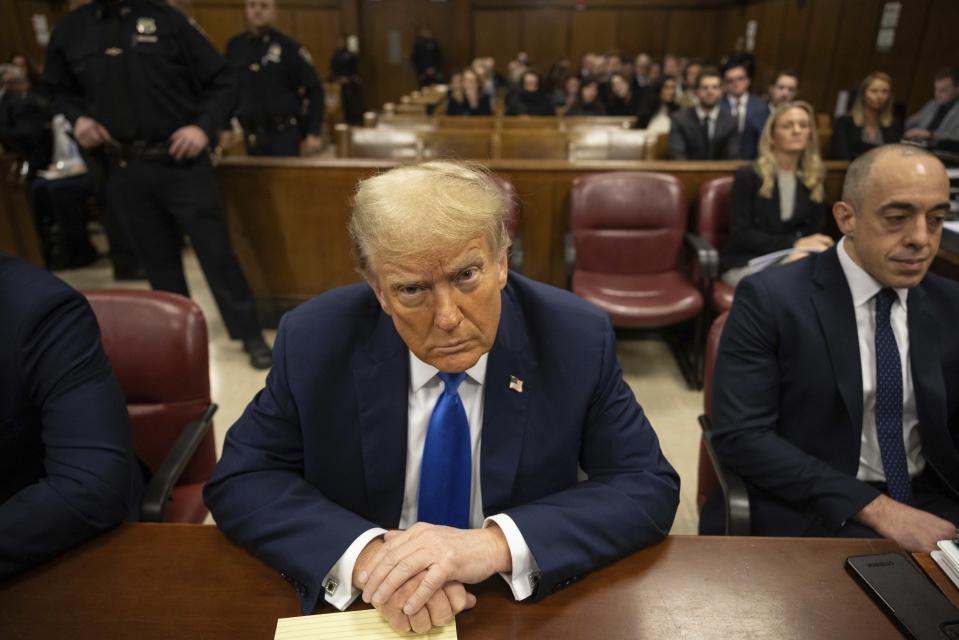 Former president Donald Trump, center, awaits the start of proceedings at Manhattan criminal court, Monday, April 22, 2024, in New York. Opening statements in Donald Trump's historic hush money trial are set to begin. Trump is accused of falsifying internal business records as part of an alleged scheme to bury stories he thought might hurt his presidential campaign in 2016. (AP Photo/Yuki Iwamura, Pool)