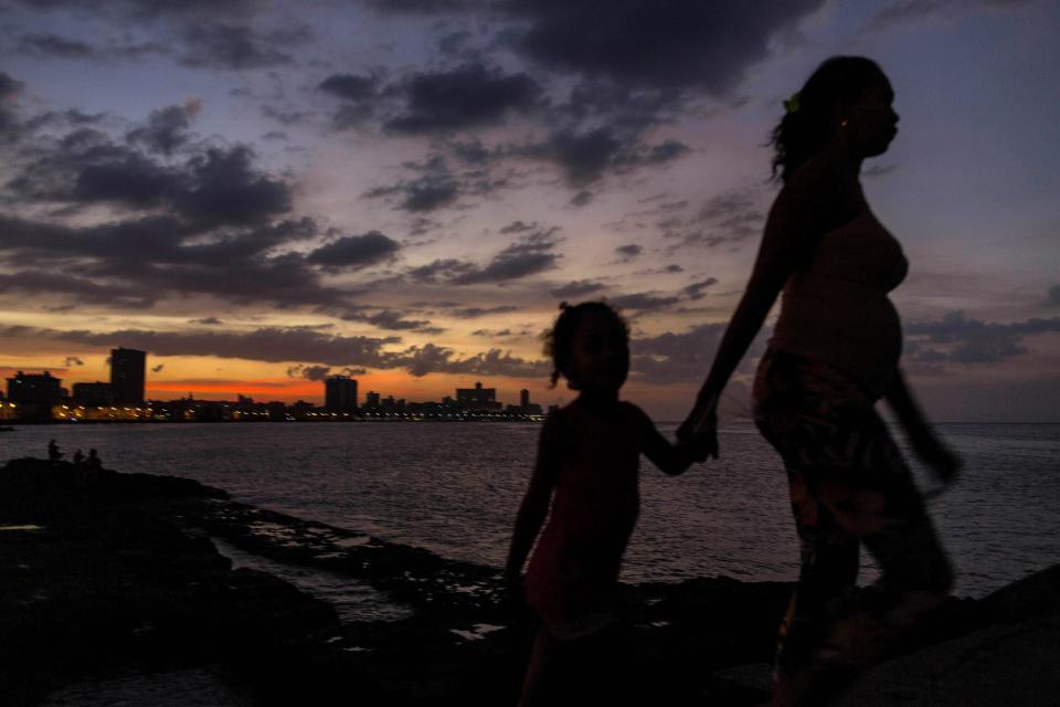 En esta foto del 3 de enero del 2015, una mujer lleva a una niña de la mano en el malecón de La Habana, Cuba. Para un extranjero, Cuba resulta un enigma. (AP Foto/Ramón Espinosa)