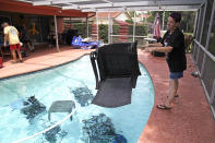 <p>Jackie Kreuter, 56, of Gulfport, Fla., tosses pool furniture in the pool Tuesday, Sept. 5, 2017 so it doesn’t fly around during the impending hurricane. Kreuter, along with her mother, husband, sister, daughter, grandson, five dogs and a bird are boarding up their home and business and leaving for Ocala to get out of Hurricane Irma’s way. (Photo: Lara Cerri/The Tampa Bay Times via AP) </p>