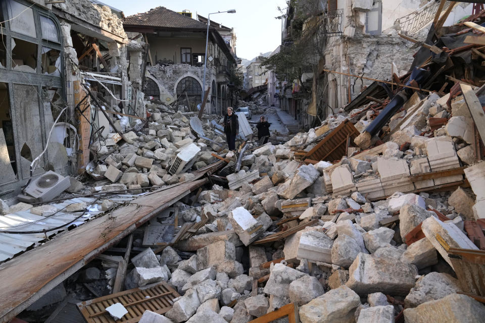 A Turkish woman stands on the debris of heritage houses that destroyed during the devastated earthquake, in the old city of Antakya, southern Turkey, Monday, Feb. 13, 2023. Antakya, known as Antioch in ancient times, has been destroyed many times by earthquakes. It was destroyed yet again by an earthquake earlier this month, and residents are wondering if its ancient glories will ever come back. (AP Photo/Hussein Malla)