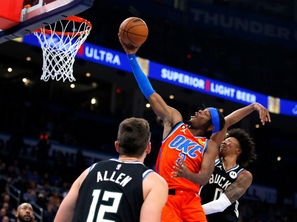 Oklahoma City 's Shai Gilgeous-Alexander (2) goes up for a basket inbetween Milwaukee's Grayson Allen (12) and MarJon Beauchamp (0) during a NBA basketball between the Oklahoma Thunder and the Milwaukee Bucks in Oklahoma City, Wednesday, Nov. 9, 2022. 