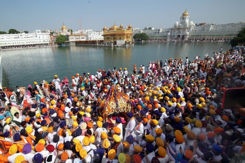 Umat Sikh membawa kitab suci Sri Guru Granth Sahib Ji dalam tandu emas khusus pada peringatan 418 tahun pengukuhan pertama Sri Guru Granth Sahib Ji di Kuil Emas yang berada di Distrik Amritsar, Negara Bagian Punjab, India utara, pada 28 Agustus 2022. (Xinhua/Stringer)