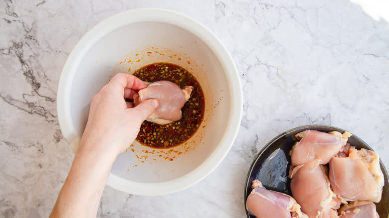 Adding chicken breasts to marinade