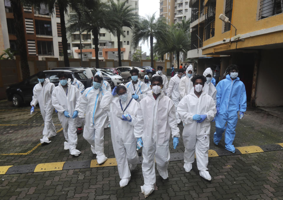 Health workers arrives to screen people for COVID-19 symptoms at a residential building in Mumbai, India, Sunday, July 26, 2020. India is the third hardest-hit country by the pandemic in the world after the United States and Brazil. (AP Photo/Rafiq Maqbool)