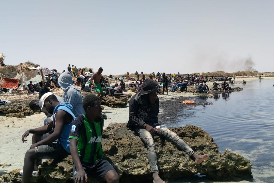 In this photo taken by 29-year-old migrant from the Ivory Coast, a group of sub-Saharan Africans is seen stranded on a beach allegedly at the Tunisian-Libyan border on Thursday 6 July 2023. The migrants, including women and small children, told AP by phone they were rounded up by Tunisian authorities since Saturday and progressively dumped on the border where they have been stuck for days. (UGC via AP)