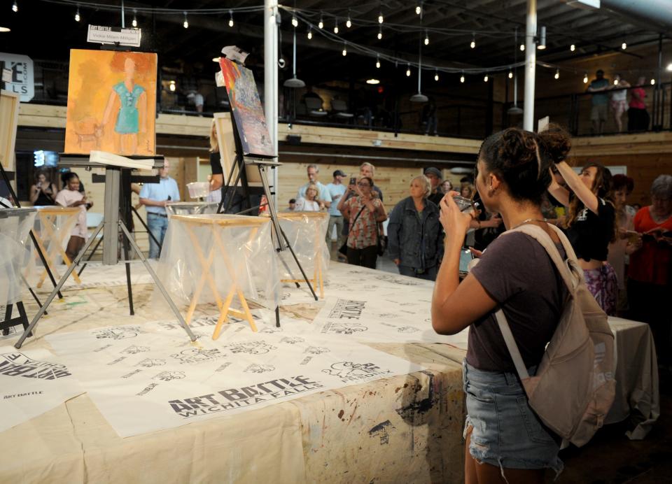 People walk around and vote on the finished works from the first round of Art Battle Wichita Falls Saturday, June 22, 2019, inside The Warehouse.