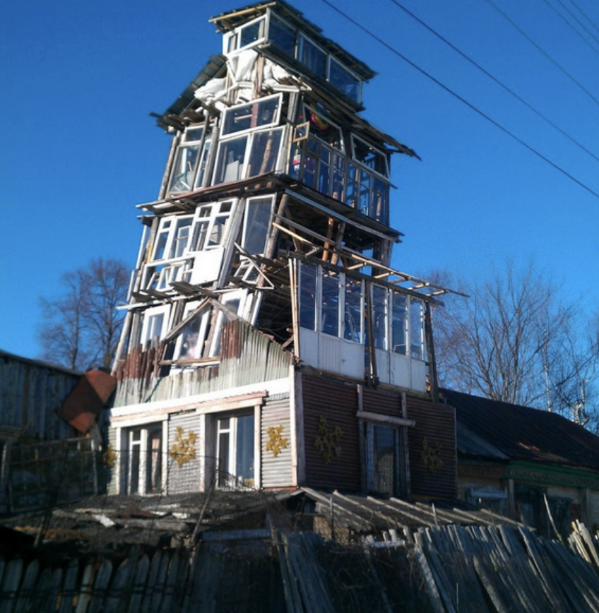 A house built up with multiple levels of window panels that looks like it's going to fall apart