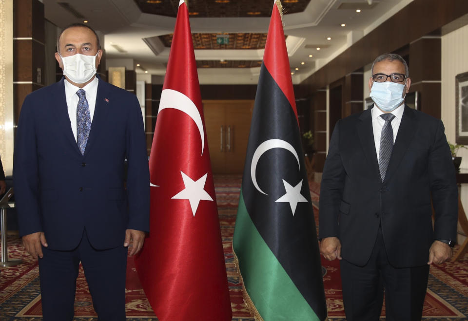 FILE - In this Aug. 6, 2020 file photo, Turkey's Foreign Minister Mevlut Cavusoglu, left, and Khalid Al-Mishri, Head of the Libyan High Council of State, pose for a photo before their talks, in Tripoli, Libya. The confirmed death toll from the coronavirus has gone over 50,000 in the Middle East as the pandemic continues. That's according to a count Thursday, Sept. 3, 2020, from The Associated Press, based on official numbers offered by health authorities across the region. Those numbers still may be an undercount, though, as testing in war-torn nations like Libya and Yemen remains extremely limited. (Fatih Aktas/Turkish Foreign Ministry via AP, Pool, File)