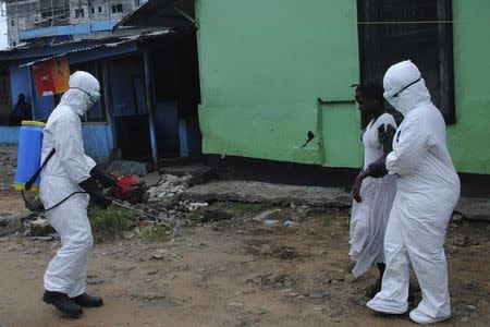 Health workers spray bleach solution on a woman suspected of having contracted the Ebola virus in Monrovia, Liberia, September 15, 2014. REUTERS/James Giahyue