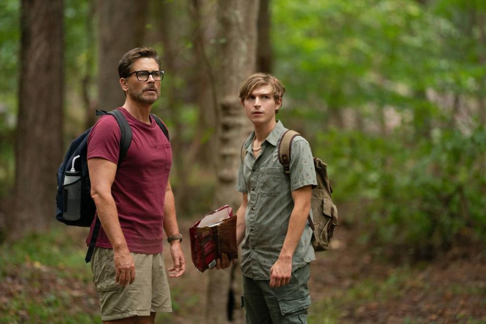 a father and son search the woods for a lost dog in a scene from dog gone, a good housekeeping pick for bet kids' movies 2023