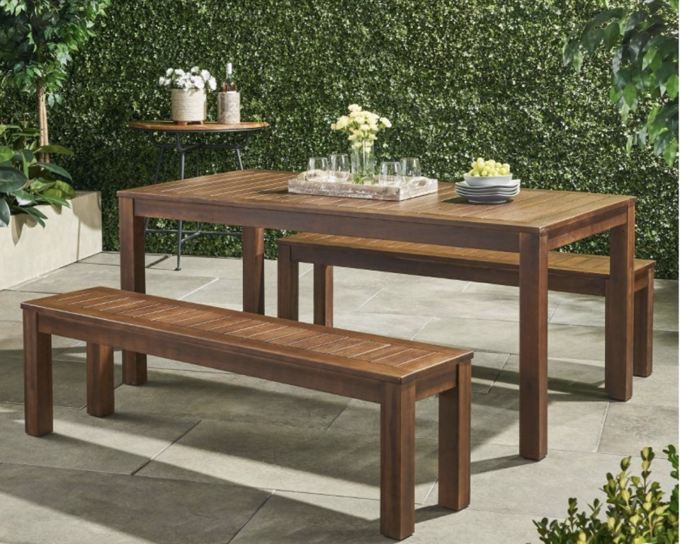 Christopher Knight Home dark brown Outdoor Manila Dining Set on a patio with a greenery backdrow