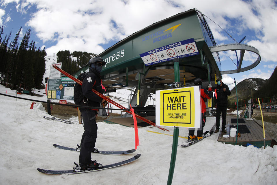 A lone member of the ski patrol waits to board a lift at the reopening of Arapahoe Basin Ski Resort, which closed in mid-March to help in the effort to stop the spread of the new coronavirus Wednesday, May 27, 2020, in Keystone, Colo. An executive order signed by President Donald Trump barring a wide variety of foreign visas has created another hurdle for ski resorts as they struggle to hire enough temporary workers to fill crucial jobs. (AP Photo/David Zalubowski, File)