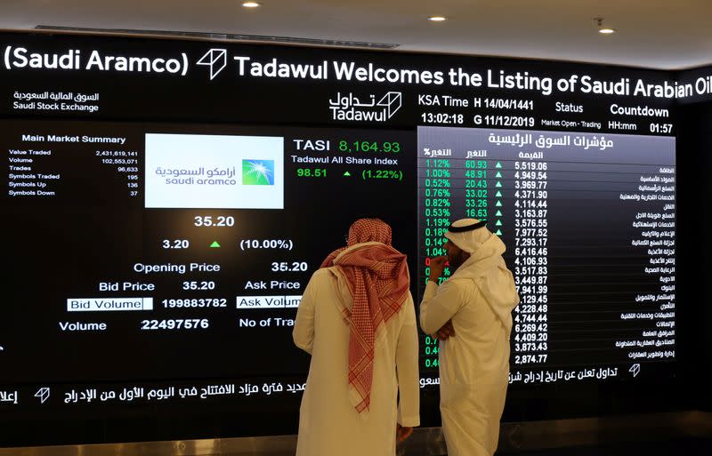 Investors monitor a screen displaying stock information at the Saudi Stock Exchange (Tadawul), in Riyadh