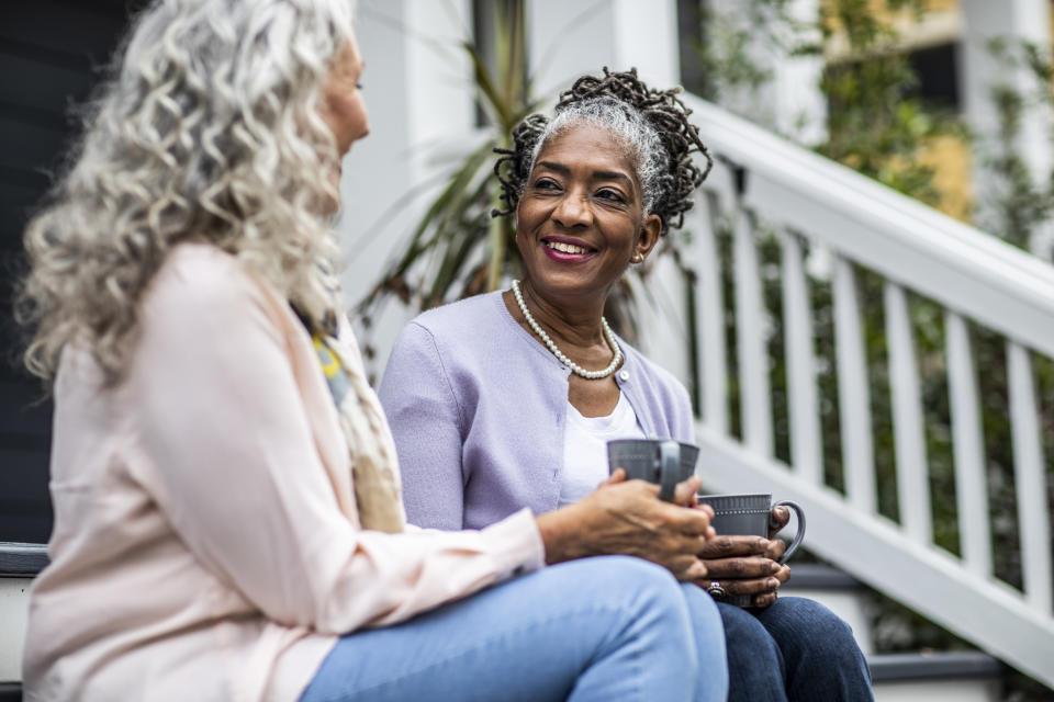 Senior women having coffee in front of suburban home. Support networks become more important for senior women when they become single. (Getty)