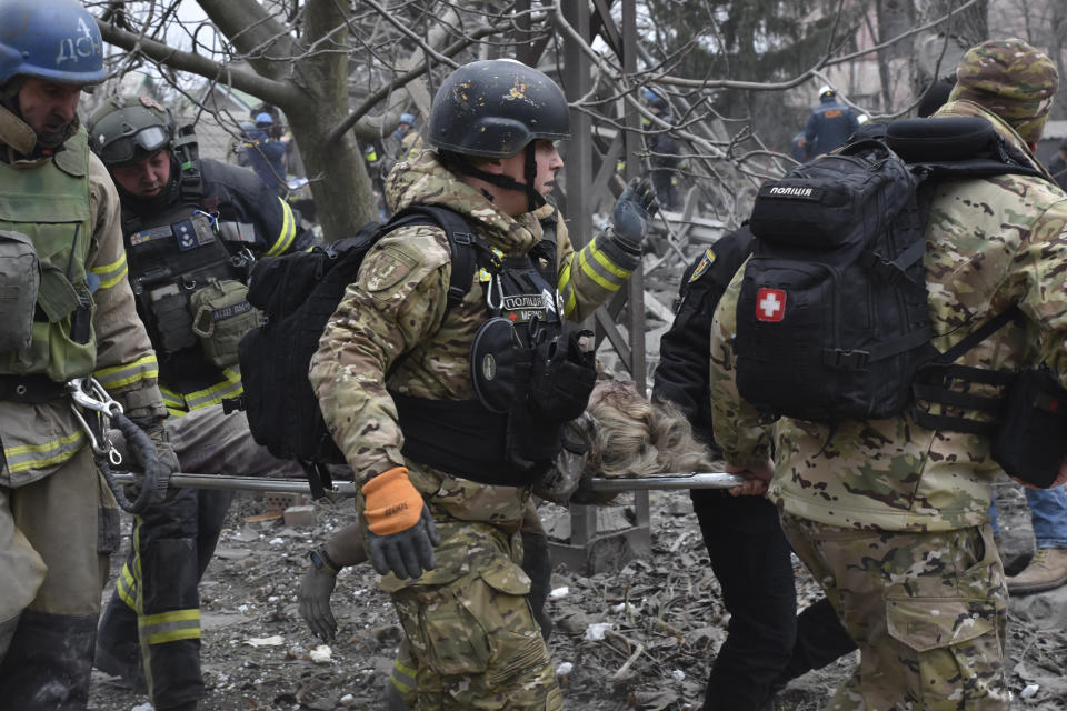 Ukrainian emergency workers and servicemen carry the body of a resident killed in Russia's massive air attack in Zaporizhzhia, Ukraine, Friday, Dec. 29, 2023. (AP Photo/Andriy Andriyenko)