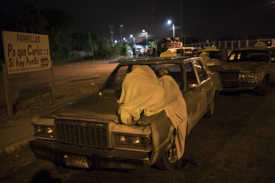 A man sleeps on top of his car as he waits in line to fill up outside a gas station in Maracaibo, Venezuela, May 23, 2019. In cities across the country, weary drivers wait for scarce gasoline in long lines at service stations. (AP Photo/Rodrigo Abd)