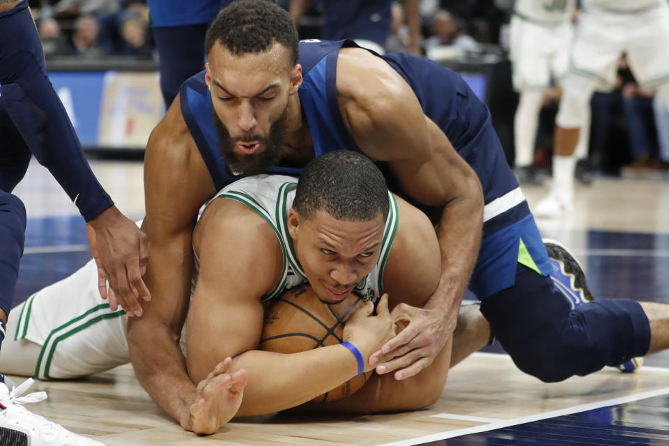 Boston Celtics forward Grant Williams, bottom, grabs for the ball as Minnesota Timberwolves center Rudy Gobert, top, forces a jump-ball call during the fourth quarter of an NBA basketball game Wednesday, March 15, 2023, in Minneapolis. The Celtics won 104-102. (AP Photo/Bruce Kluckhohn)
