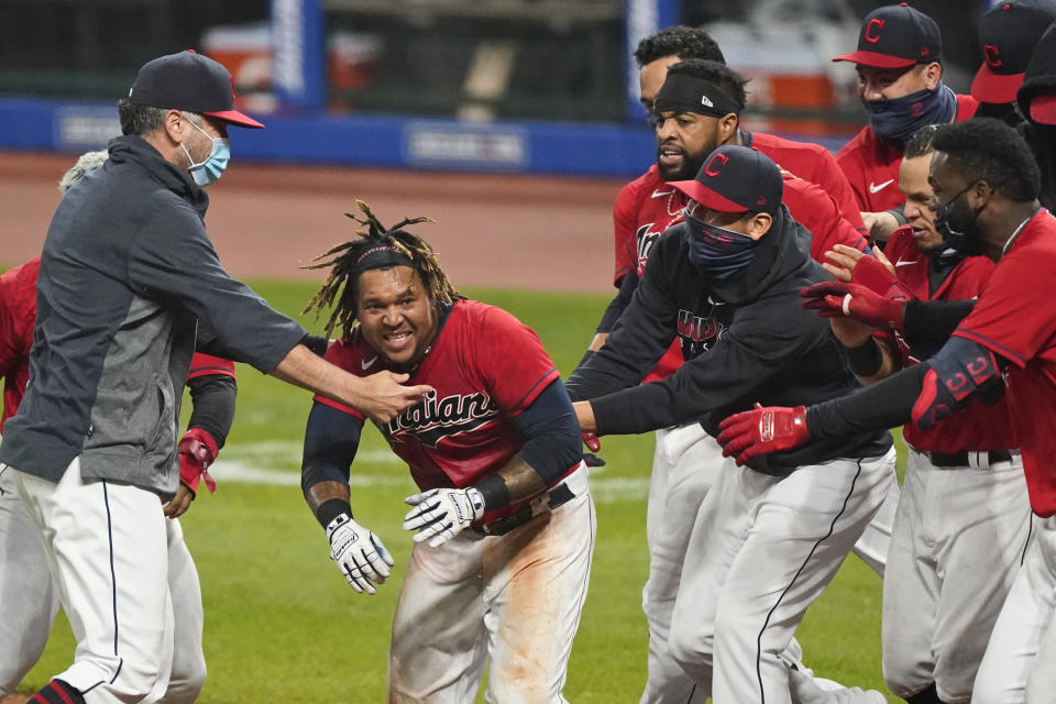 Cleveland Indians' Jose Ramirez, center, is mobbed after Ramirez hit a three-run home run in the tenth inning of a baseball game against the Chicago White Sox, Tuesday, Sept. 22, 2020, in Cleveland. (AP Photo/Tony Dejak)