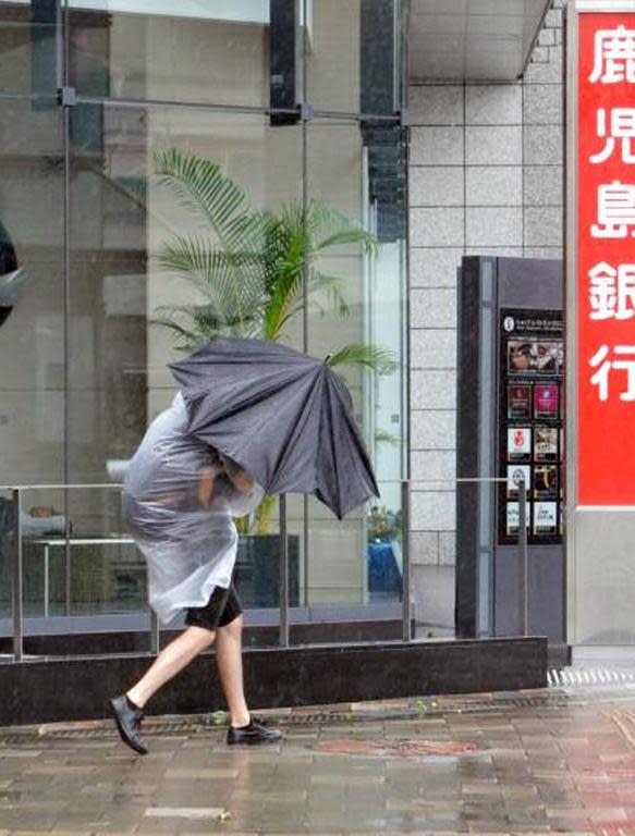 A pedestrian walks against strong wind at Kagoshima, Japan's southern island of Kyushu on October 13, 2014