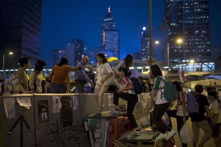 Protesters of the Occupy Central movement climb over a divider used by demonstrators to block the main road leading to the financial Central district in Hong Kong October 7, 2014. REUTERS/Tyrone Siu