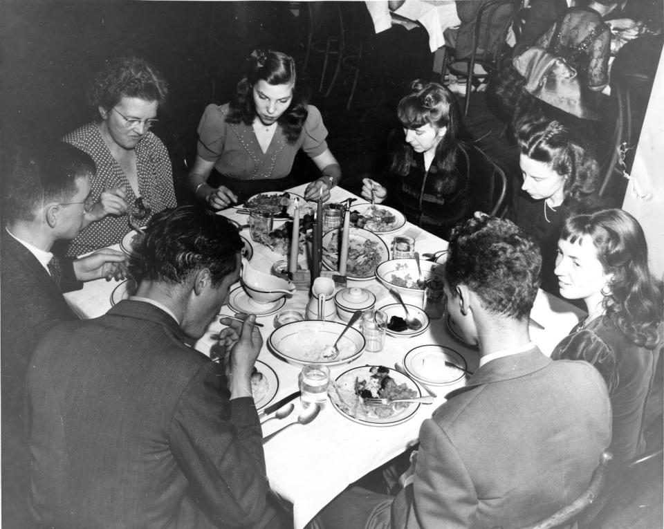 In this undated photograph, students and faculty of Black Mountain College enjoy dinner together.