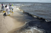 Workers clean up oil balls from the Deepwater Horizon oil spill as the surf brings more onto a beach in Waveland, Mississippi July 7, 2010. REUTERS/Lee Celano